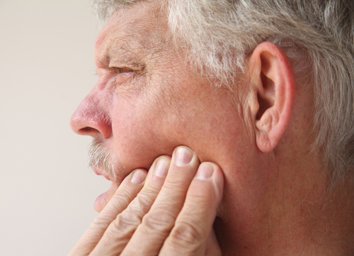 man pressing on his jaw from pain