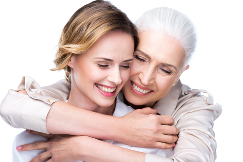 middle aged woman and senior woman hugging and smiling