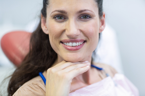 Smiling female patient sitting on dentist chair